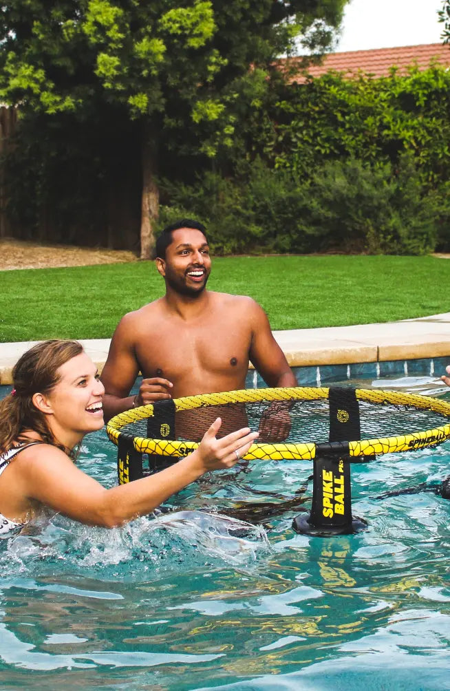 Two Spikeball players having a good time using the Spikebouy kit in a pool